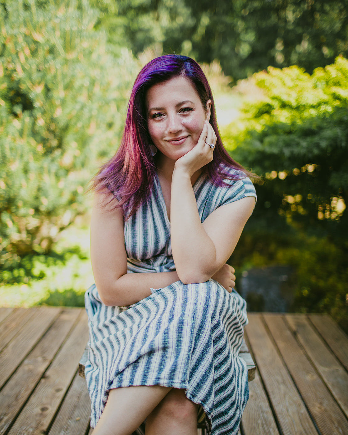Woman with colorful hair sitting on a wooden bench outdoors
